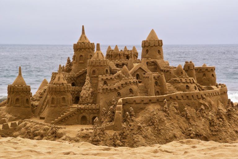 Chateau de sable sur la plage avec avec l'océan en arrière-plan.