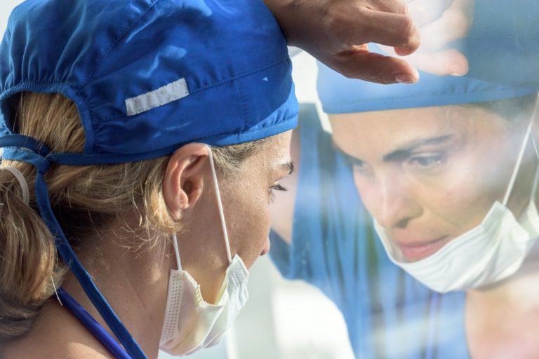 Femme médecin l'air grave regardant à travers une fenêtre