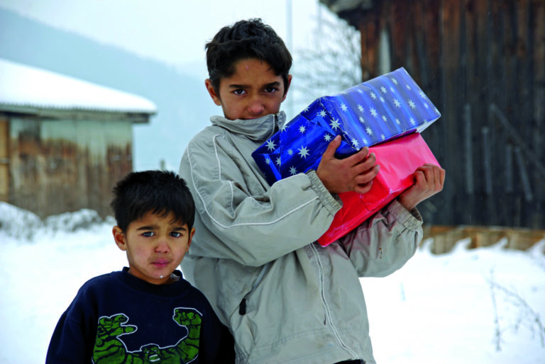 Deux enfants, dehors dans la neige recevant des paquets de Noël