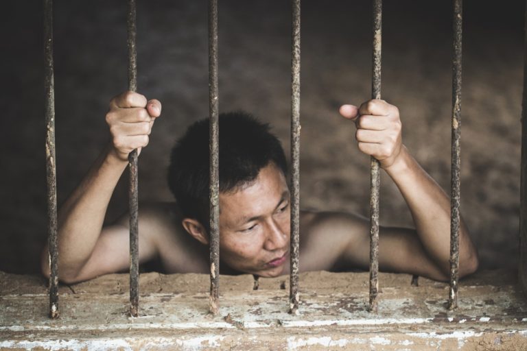 Homme en prison tenant les barreaux. Image d'illustration