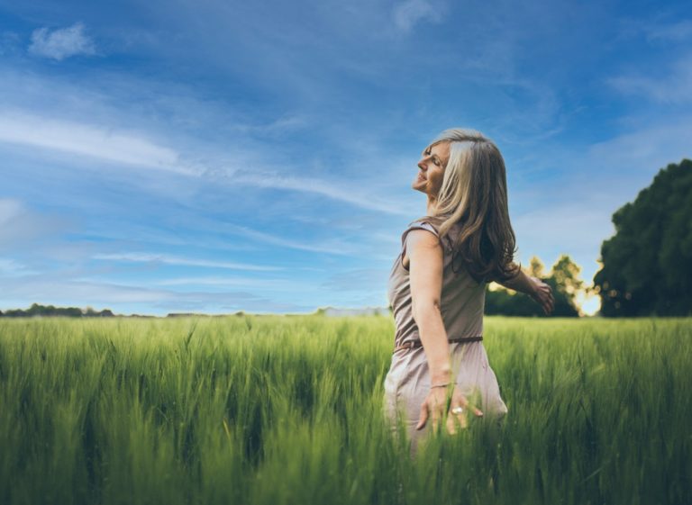 Une femme dansant dans un champ de verdure, les cheveux au vent