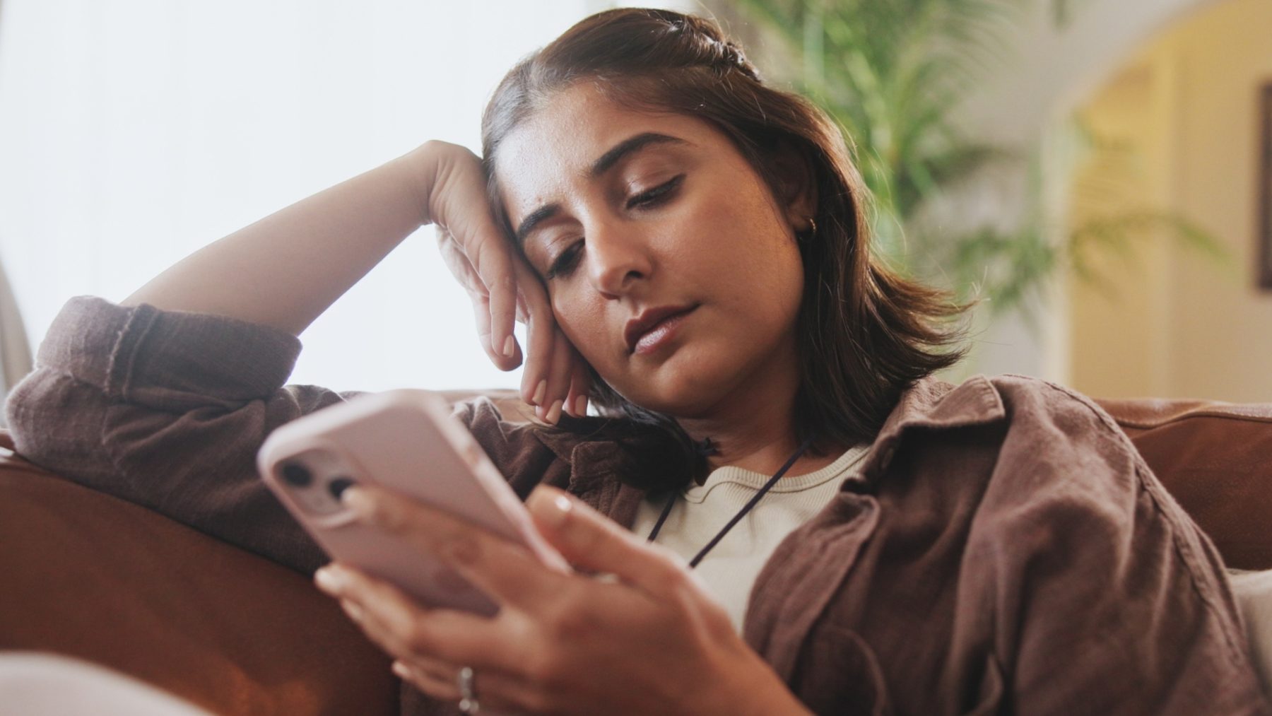 Une jeune femme scrolle sur son téléphone d'un air un peu détaché.