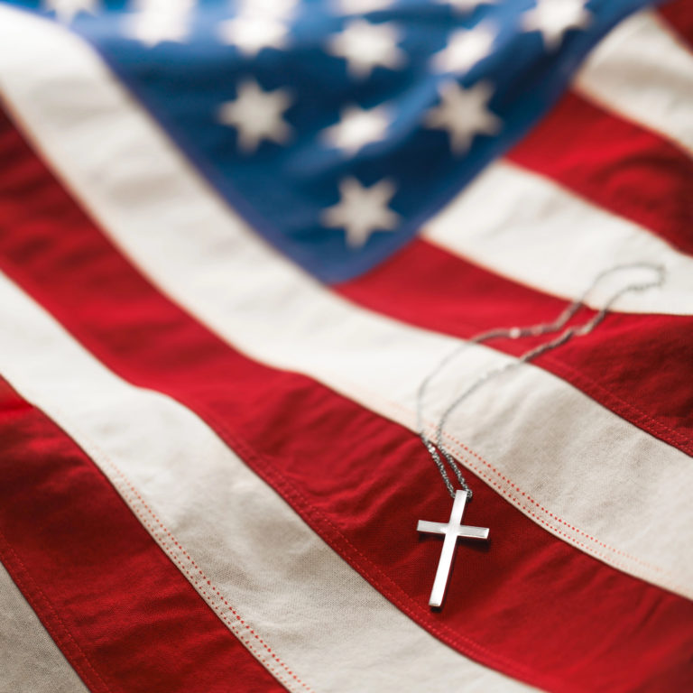 Un pendentif en forme de croix placée sur un drapeau états-unien illustre le nationalisme chrétien