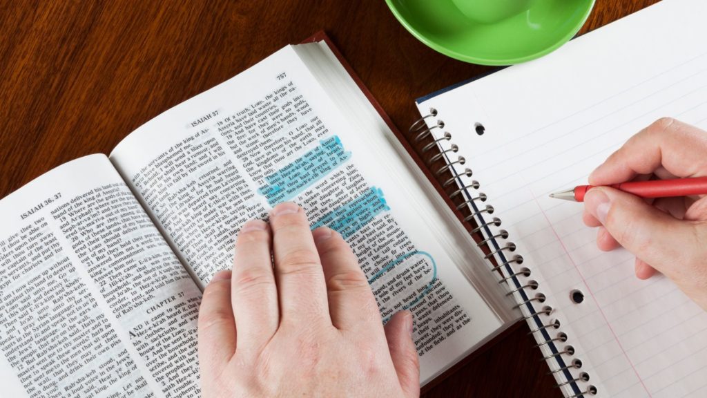 Quelqu'un étudie la Bible en prenant des notes.