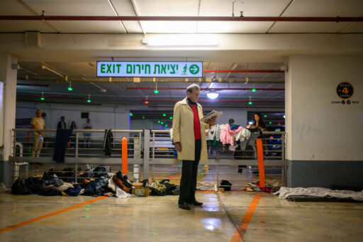 Un homme lit le journal alors qu'il se réfugie dans un parking souterrain et un abri, alors qu'une alerte et une sirène annonçant l'arrivée d'un missile iranien retentissent, le 12 mars 2026 à Tel-Aviv, en Israël.