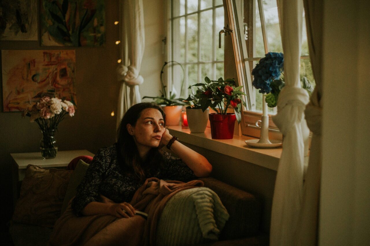 Femme seule regardant par la fenêtre, illustrant la solitude des conjoints de pasteurs