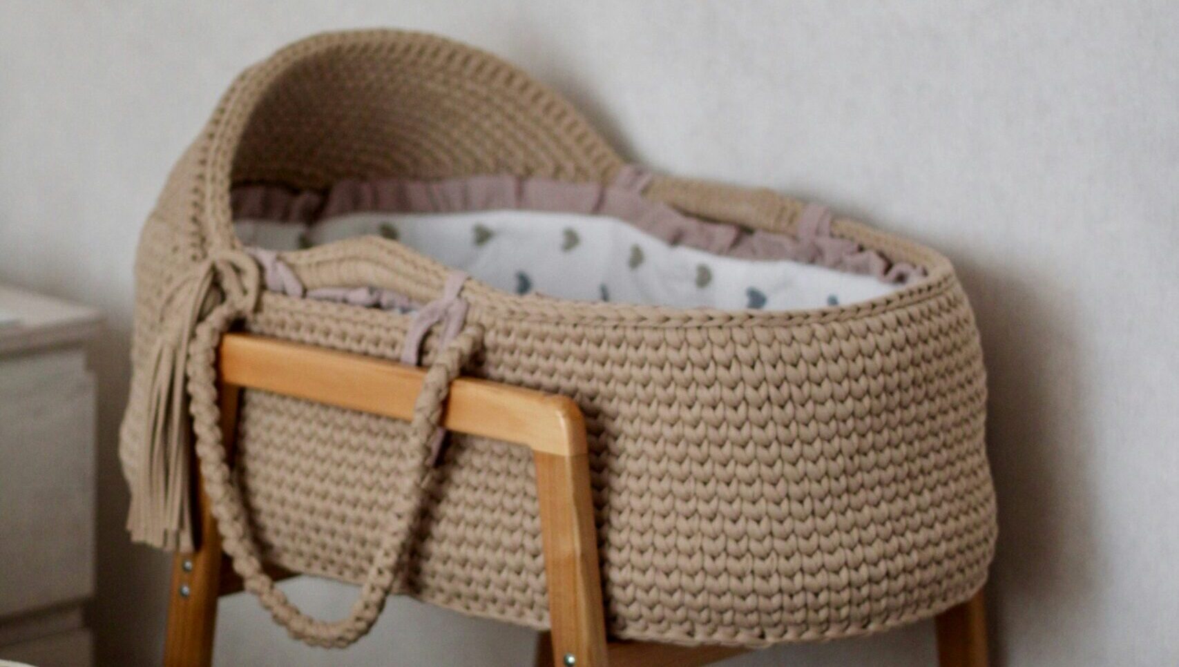 Chambre de bébé vide avec un berceau en osier, symbolisant l'hésitation d'une génération face à la parentalité