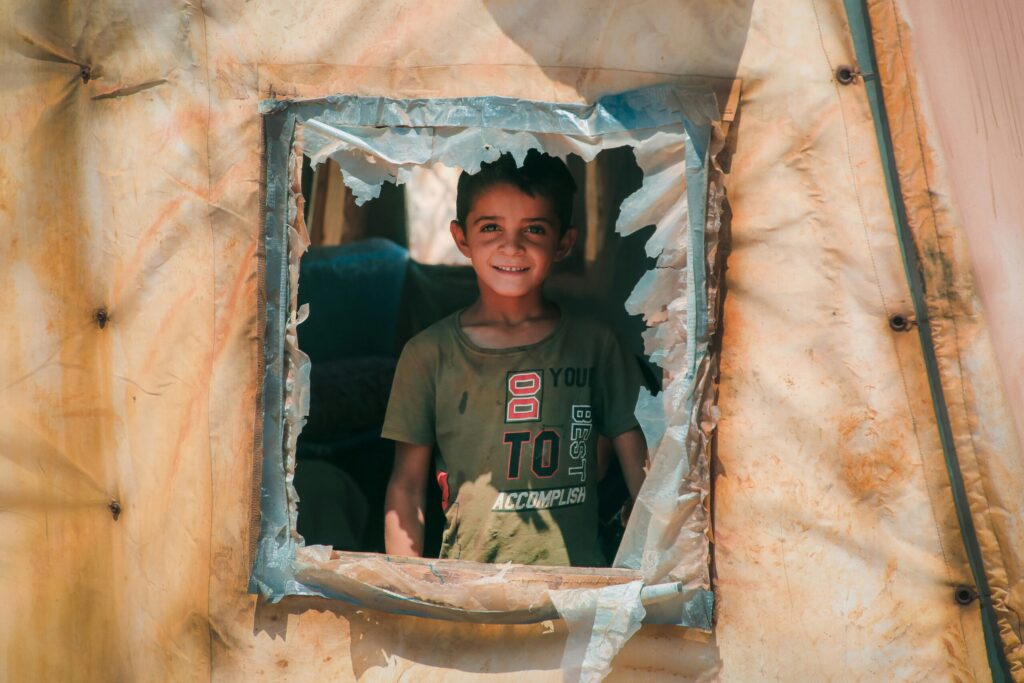 Un enfant souriant à une fenêtre dans un environnement de guerre