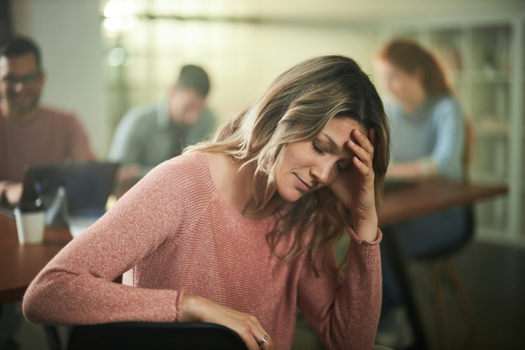 Femme épuisée, la tête dans la main, à son poste de travail