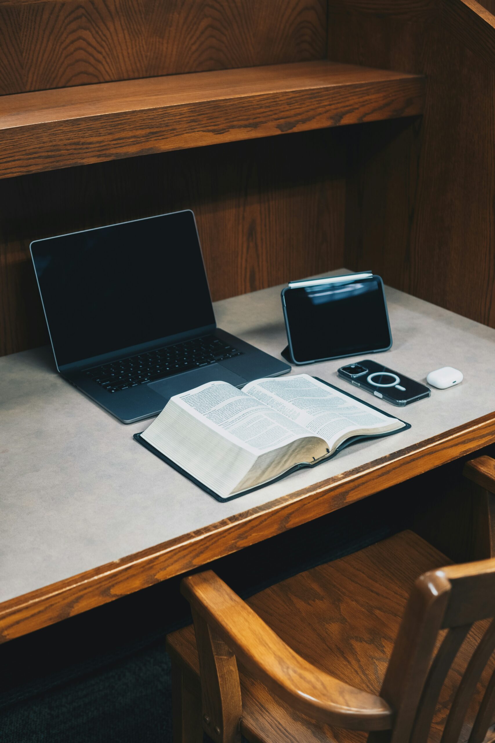 Une Bible, un ordinateur portable et un téléphone posés sur un bureau en bois