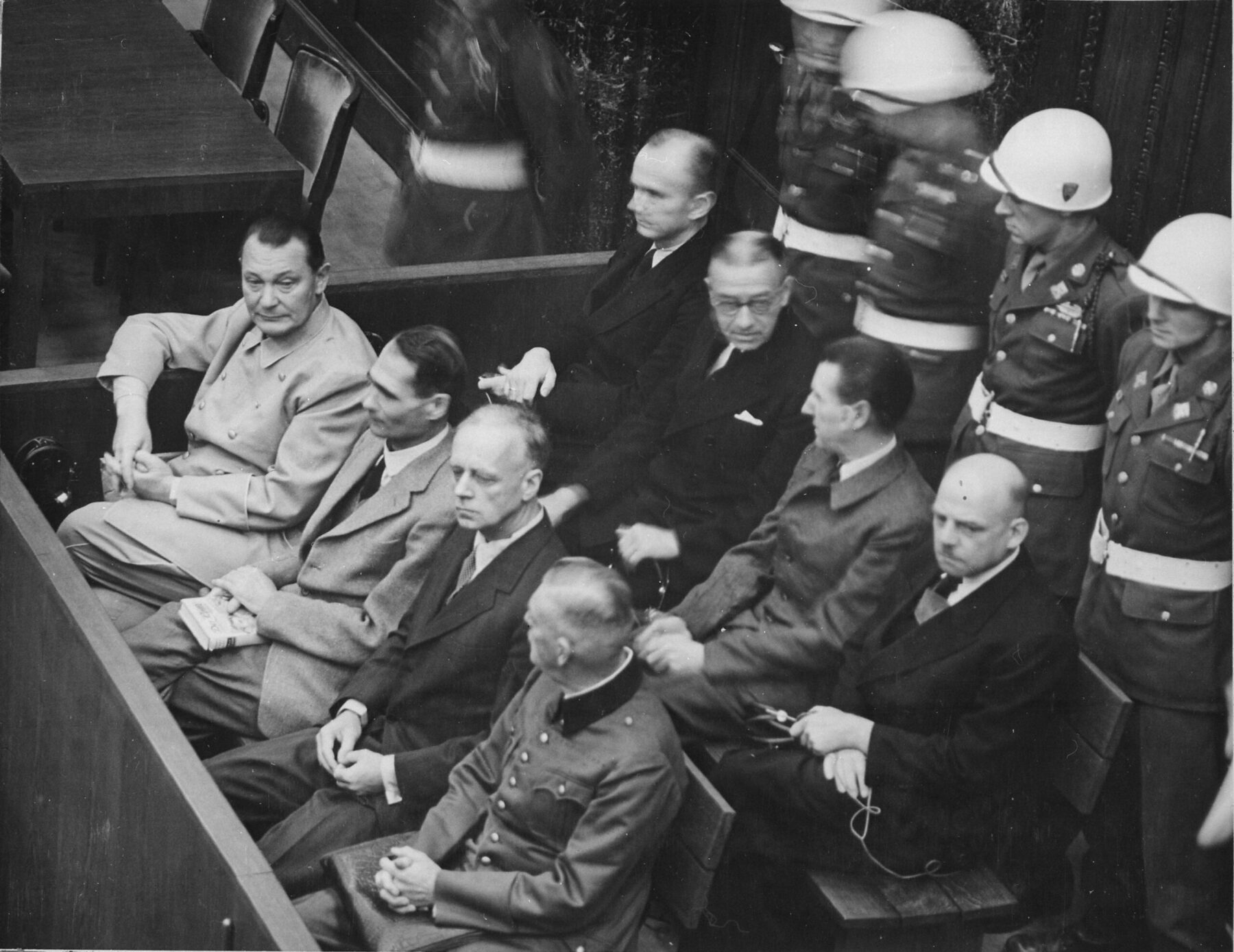 Le banc des accusés au procès de Nuremberg, gardé par des soldats américains casqués